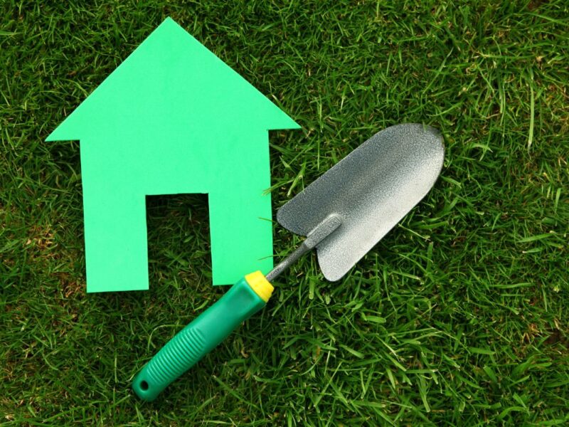 Green cut out house with garden trowel on grass- How to prepare your outdoor space for a successful house sale